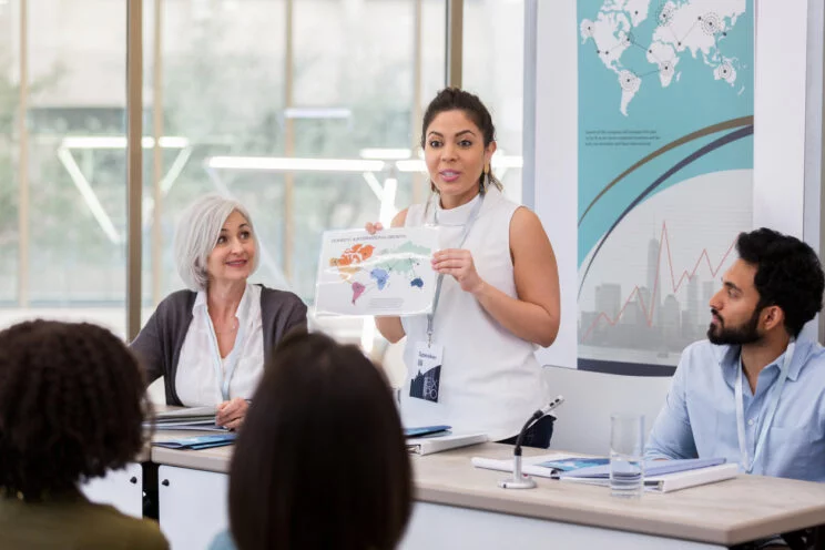 Confident international businesswoman show map during conference