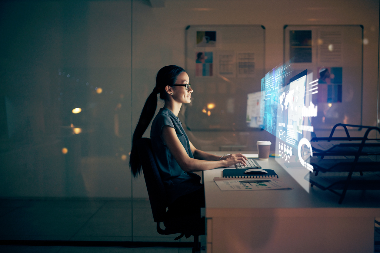 Shot of a young programmer using a computer at night in a modern office